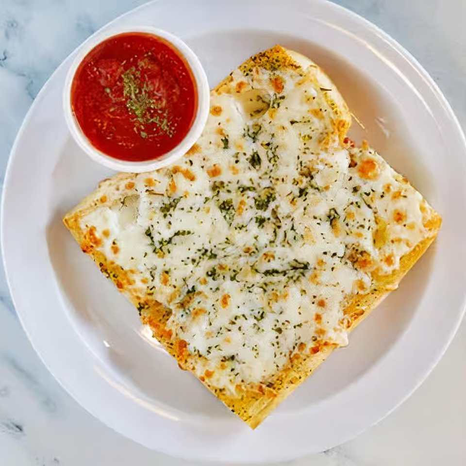 Cheesy garlic bread with herbs and a side of red marinara sauce on a white plate.