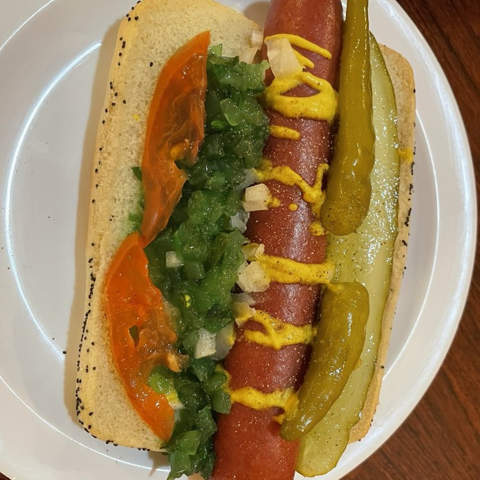 A Chicago-style hot dog with mustard, relish, tomato, and pickles on a poppy seed bun.